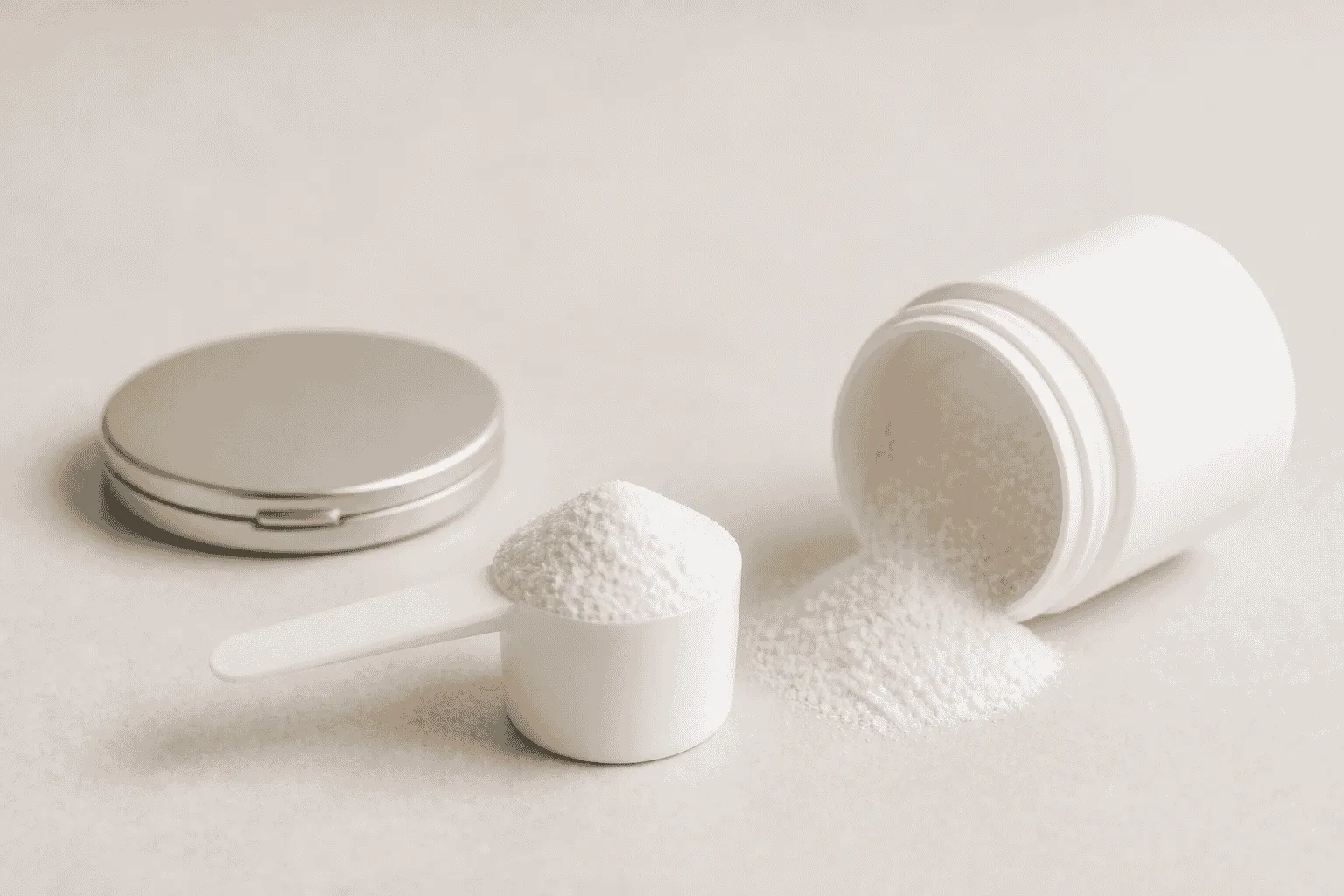 White collagen powder scoop and spilled powder beside a closed compact mirror on a cream studio surface