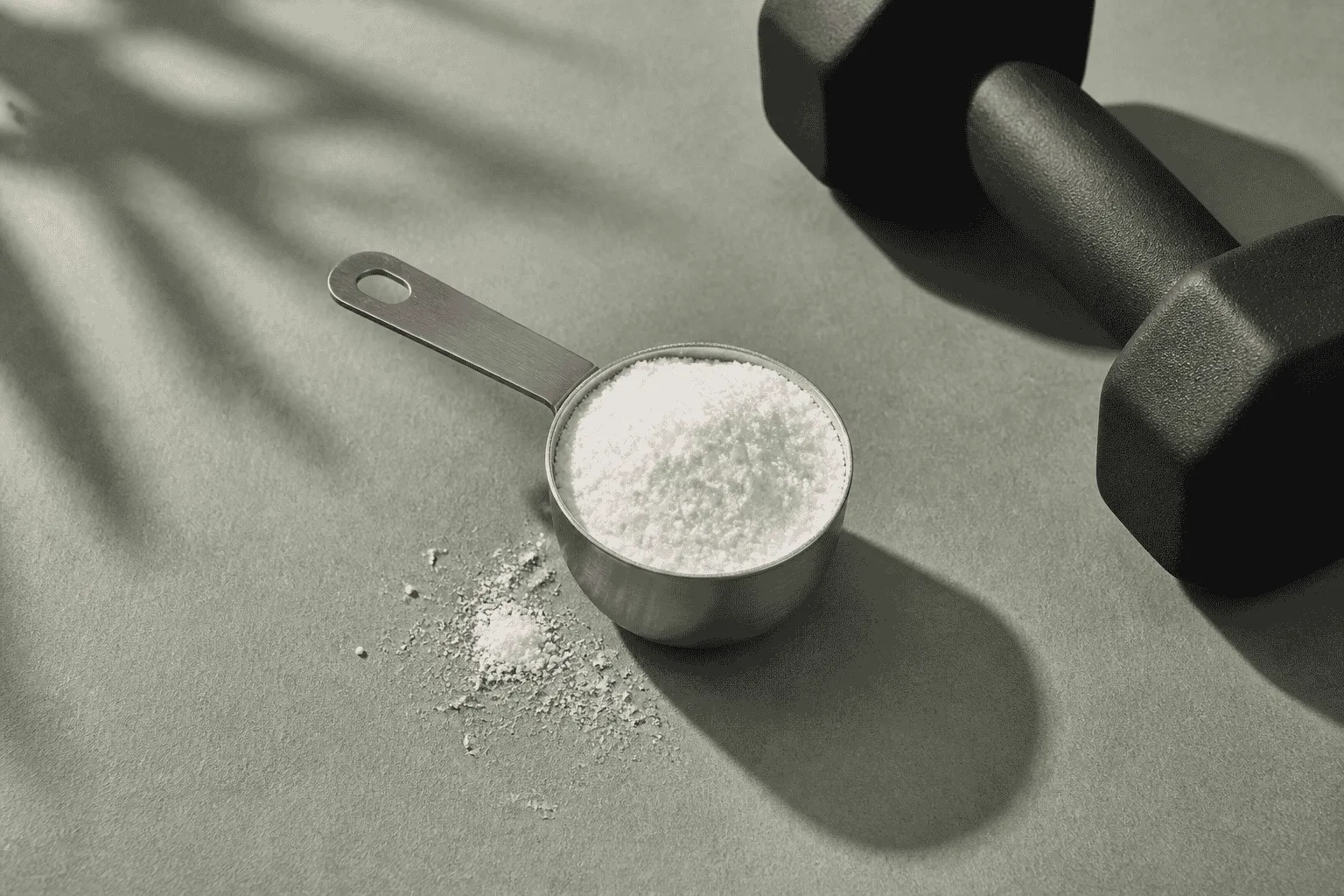 Creatine powder scoop beside dumbbells and a calendar marking midlife, representing muscle and energy support for women over forty